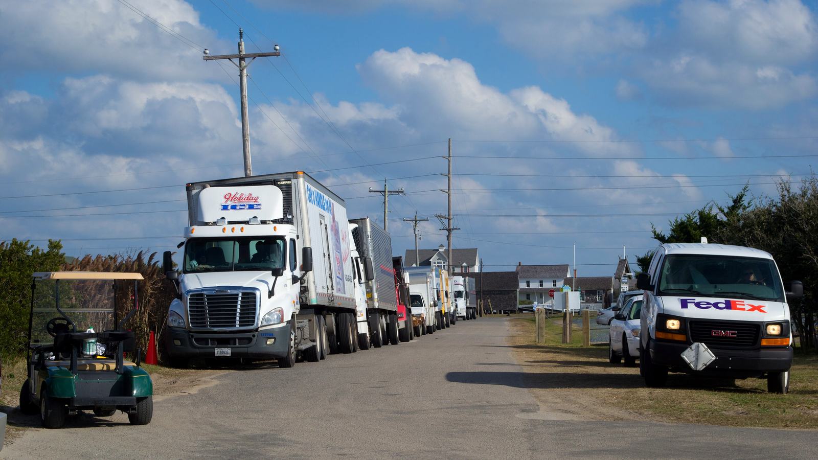 Delivery trucks and vans lined up on a road in Rodanthe, waiting to board an NCDOT ferry
